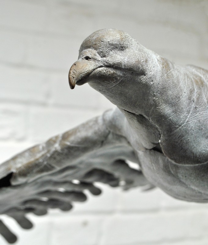 BIRD IN HAND - Detail: a bronze bird in flight made out of hand prints